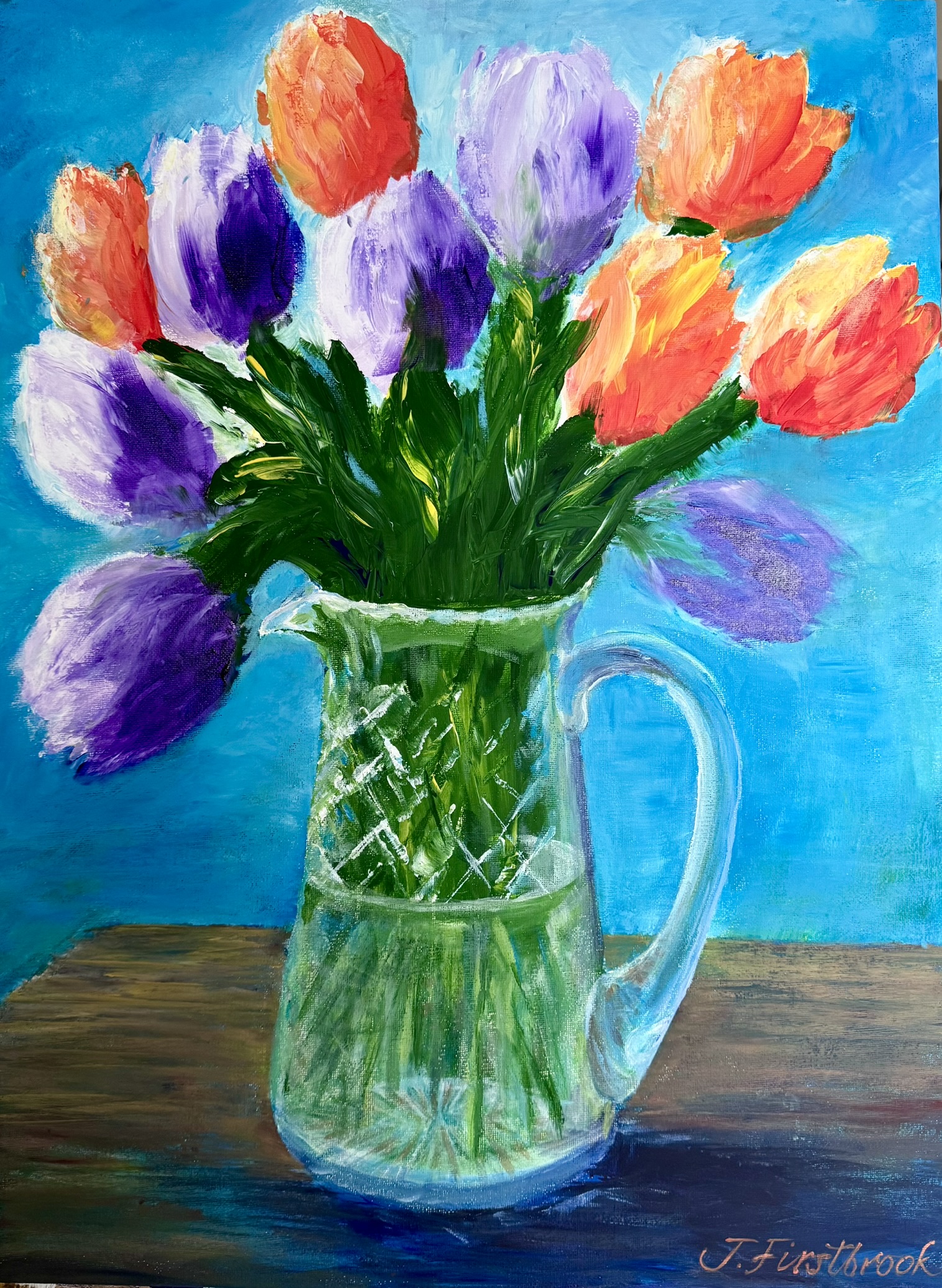 Glass vase of tulips in purple and orange.
